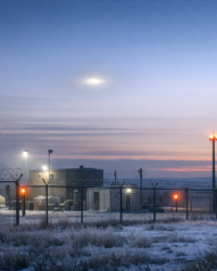 Documentary-style view of a remote Montana missile site at dawn with a faint unexplained light in the sky.