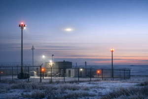 Documentary-style view of a remote Montana missile site at dawn with a faint unexplained light in the sky.
