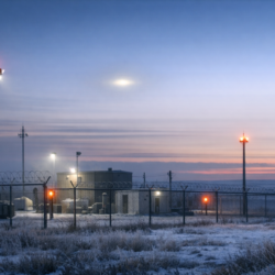 Documentary-style view of a remote Montana missile site at dawn with a faint unexplained light in the sky.